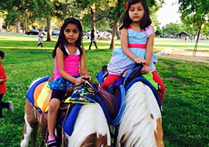2 young girls riding pony's at an event in Fresno at Gujarati Samaj.